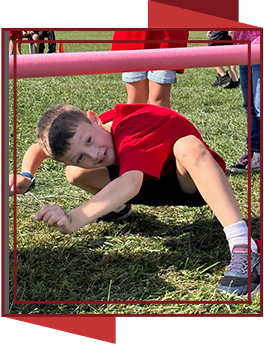 Boy crouching under a bar during field day activities